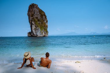 Kumsaldaki çift, Koh Poda Tayland, Tayland 'ın Krabi ilindeki Poda Adası' nın güzel manzarası. Bu adanın beyaz kumsalı var ve kristal berrak suyla çevrili.