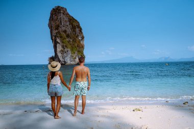 Kumsaldaki çift, Koh Poda Tayland, Tayland 'ın Krabi ilindeki Poda Adası' nın güzel manzarası. Bu adanın beyaz kumsalı var ve kristal berrak suyla çevrili.
