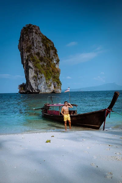 Guy in swim short on the beach of Koh poda Island Krabi Thailand, men in yellow short on the beach on a bright sunny day with blue sky