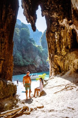 Kireçtaşı kayalıklarındaki kadın ve erkekler Koh Poda Krabi Tayland 'daki gizli kumsala bakıyorlar.