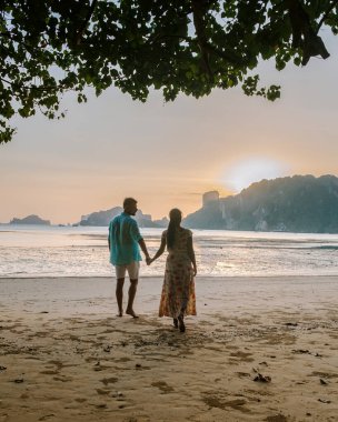 couple on the beach during sunset at the tropical Krabi area Thailand, Ao Nam Mao beach Krabi Ao Nang area Thailand,men and woman on the beach during luxury vacation in Thailand
