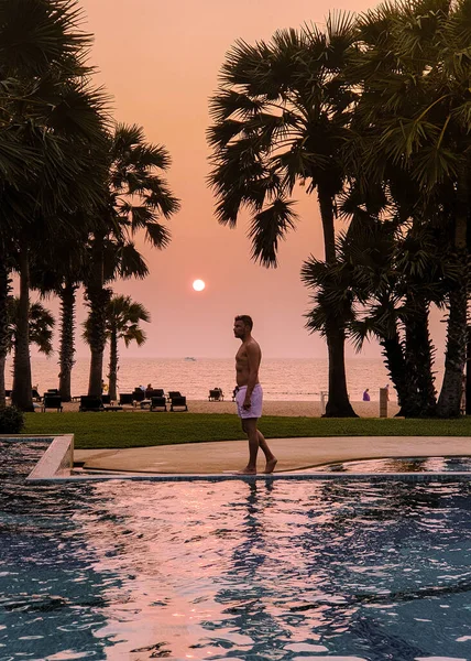 Men in swimming pool during a luxury vacation in Thailand, men and woman at luxury hotel resort in Thailand holiday in Asia — Stockfoto