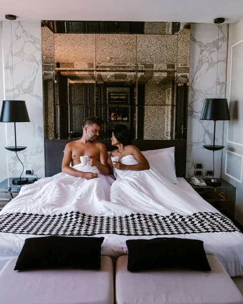 Couple having breakfast in bed, men and woman in luxury room and white bed having breakfast in bed — Stockfoto