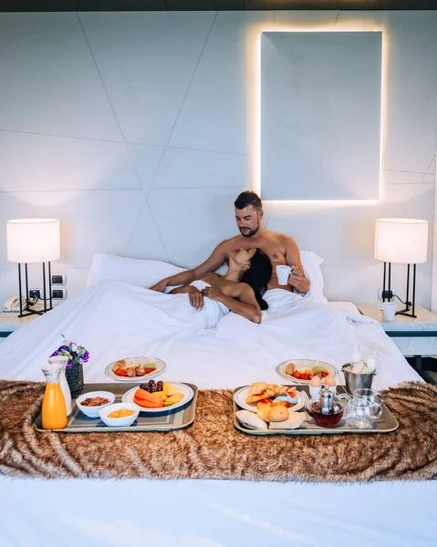 Pareja desayunando en cama, hombres y mujeres en habitación de lujo y cama blanca desayunando en cama —  Fotos de Stock