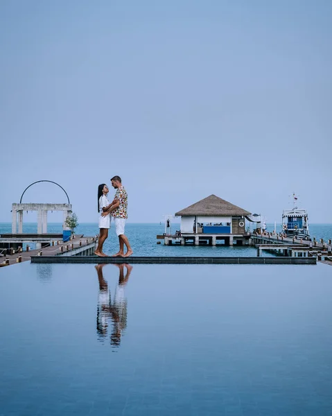 Pareja en vacaciones de lujo en Tailandia, hombres y mujeres piscina infinita con vistas al océano — Foto de Stock