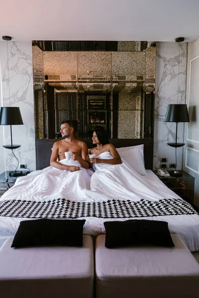 Couple having breakfast in bed, men and woman in luxury room and white bed having breakfast in bed — Stockfoto