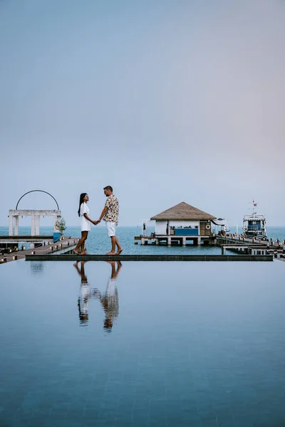 Coppia in vacanza di lusso in Thailandia passeggiando in riva al mare con piscina e cielo bleu — Foto Stock