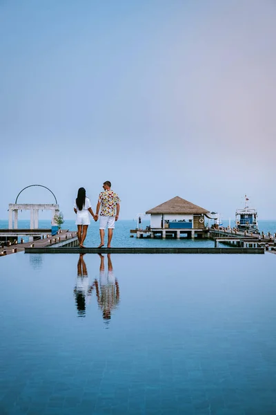 Couple on a luxury vacation in thailand walking by the ocean with pool and bleu sky — 스톡 사진