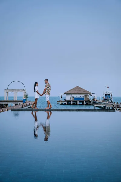 Casal em férias de luxo na Tailândia, homens e mulheres piscina infinito olhando para fora sobre o oceano — Fotografia de Stock