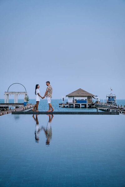 couple on luxury vacation in Thailand, men and woman infinity pool looking out over the ocean 