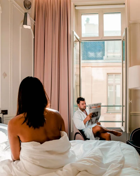 Morning wake up in bed in Paris with breakfast coffee and a newspaper, couple in bed men and woman honymoone valentine couple — Stockfoto