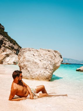 Sardinia Orosei coast Italy, guy on vacation at the Island of Sardinia on a boat trip to all the white pebble beaches some of the most beautiful beaches in Europe 
