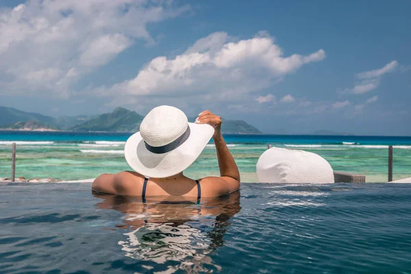 Роскошный бассейн в тропическом курорте, спокойный отдых на Сейшельских островах. La Digue, молодой человек во время заката у бассейна — стоковое фото