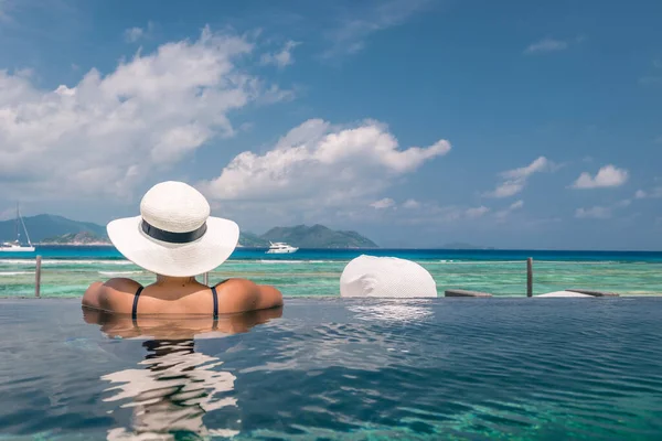 Роскошный бассейн в тропическом курорте, спокойный отдых на Сейшельских островах. La Digue, молодой человек во время заката у бассейна — стоковое фото
