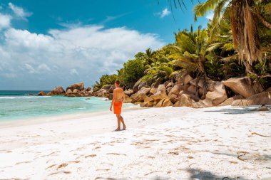 La Digue Seyşeller, Anse Source Dargent sahilinde, Praslin ve Mahe Adası yakınlarındaki La Digue Seychelles 'de günlük giysiler içinde genç bir adam.