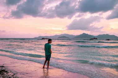 La Digue Seyşeller, Anse Source Dargent sahilinde, Praslin ve Mahe Adası yakınlarındaki La Digue Seychelles 'de günlük giysiler içinde genç bir adam.