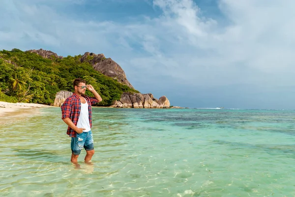 La Digue Seychely, mladý muž v neformálním oblečení na pláži v Anse Source dargent, La Digue Seychely, poblíž Praslin a Mahe Island — Stock fotografie