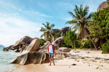 La Digue Seyşeller, Anse Source Dargent sahilinde, Praslin ve Mahe Adası yakınlarındaki La Digue Seychelles 'de günlük giysiler içinde genç bir adam.