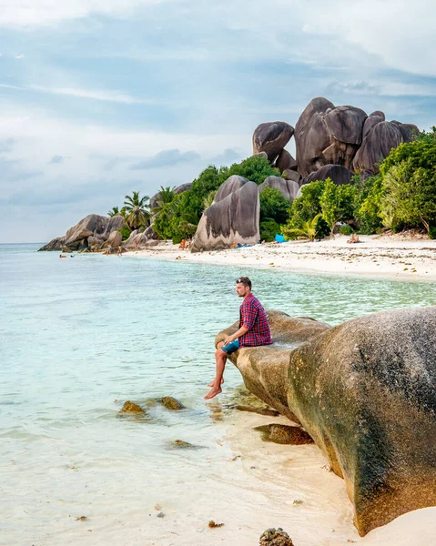 La Digue Seychelles, giovane uomo in abiti casual sulla spiaggia di Anse Source dArgent, LA Digue Seychelles, vicino a Praslin e Mahe Island — Foto Stock