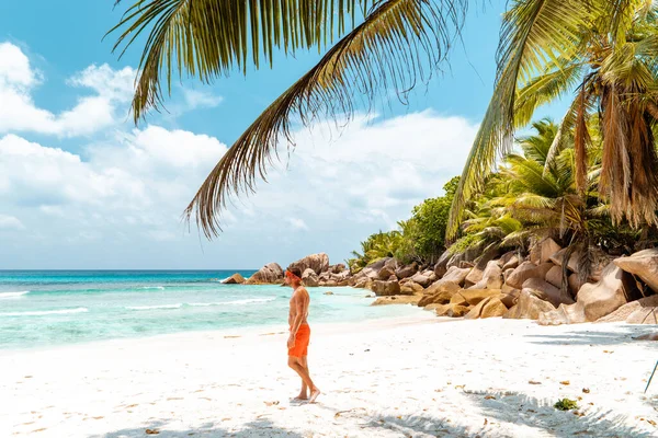 La Digue Seszele, młody człowiek w luźnych ubraniach na plaży w Anse Source dargent, La Digue Seszele, w pobliżu Praslin i Mahe Island — Zdjęcie stockowe