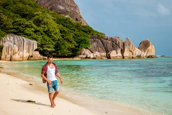 La Digue Seychely, mladý muž v neformálním oblečení na pláži v Anse Source dargent, La Digue Seychely, poblíž Praslin a Mahe Island — Stock fotografie