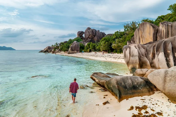 La Digue Seychelles, giovane uomo in abiti casual sulla spiaggia di Anse Source dArgent, LA Digue Seychelles, vicino a Praslin e Mahe Island — Foto Stock