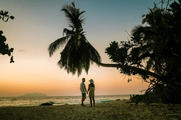 Tropical white beach at Praslin island Seychelles, happy Young couple man and woman during vacation Holiday at the beach relaxing under a palm tree — Stock Photo, Image