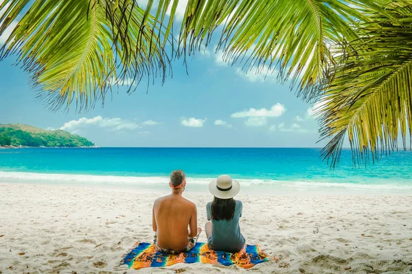 Plage de sable blanc tropicale à Praslin île de Seychelles, heureux Jeune couple homme et femme pendant les vacances Vacances à la plage se détendre sous un palmier — Photo