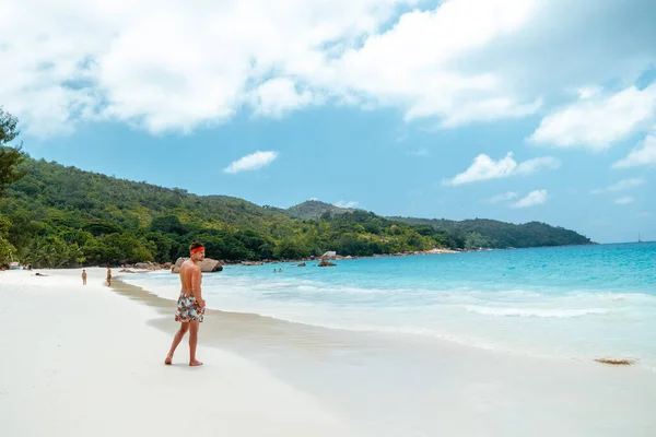Praslin Seychelles, jeunes hommes sur la plage tropicale avec palmier, homme de plage blanc marchant sur l'île des Seychelles, hommes bronzant en vacances tropicales — Photo