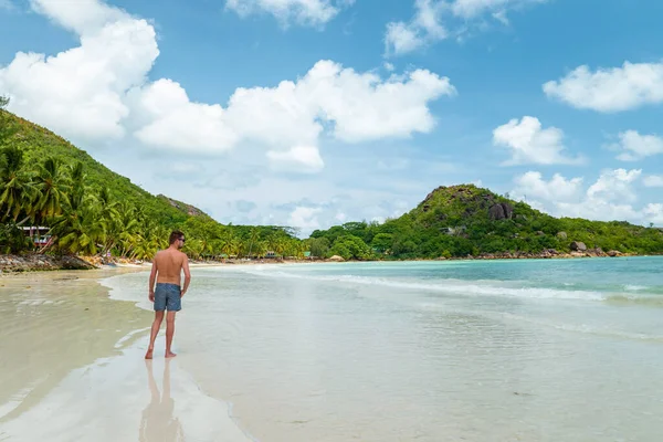 Praslin Seychellerna, unga män på tropisk strand med palm, vit strandman promenader Seychellerna Island, garvning män på tropisk semester — Stockfoto