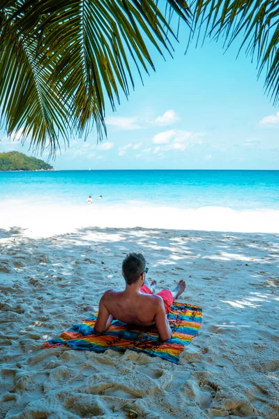 Praslin Seychelles, giovani sulla spiaggia tropicale con palma, uomo bianco sulla spiaggia a piedi Seychelles Island, uomini abbronzanti in vacanza tropicale — Foto Stock