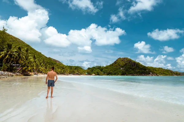 Praslin Seychelles, young men on tropical beach with palm tree, white beach man walking Seychelles Island, tanning men on tropical vacation — стоковое фото