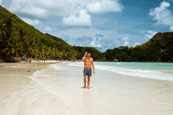 Praslin Seychellen, junge Männer am tropischen Strand mit Palme, weißer Strandmann auf den Seychellen, Sonnenanbeter im Tropenurlaub — Stockfoto