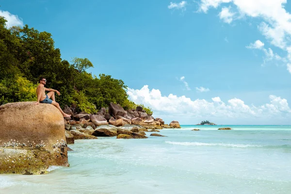 Praslin Seszele, młodzi mężczyźni na tropikalnej plaży z palmą, biały człowiek na plaży spacerujący po Seszelach, mężczyźni opalający się na tropikalnych wakacjach — Zdjęcie stockowe