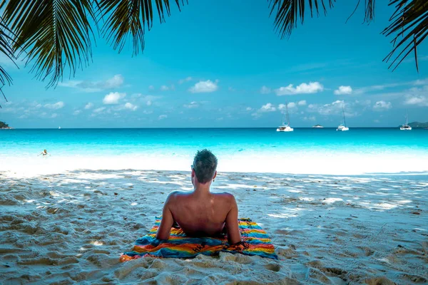 Praslin Seychellen, junge Männer am tropischen Strand mit Palme, weißer Strandmann auf den Seychellen, Sonnenanbeter im Tropenurlaub — Stockfoto