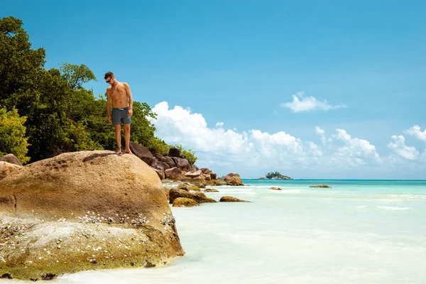 Praslin Seychelles, jeunes hommes sur la plage tropicale avec palmier, homme de plage blanc marchant sur l'île des Seychelles, hommes bronzant en vacances tropicales — Photo