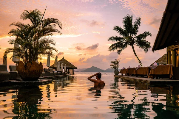 Piscina di lusso in località tropicale, vacanze rilassanti nelle isole Seychelles. La Digue, Giovane durante il tramonto in piscina — Foto Stock