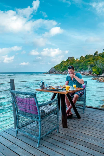 Muži se snídaní oceán přední Seychely, muži oceánfrant sedí u stolu jíst brekafast Seychellen — Stock fotografie