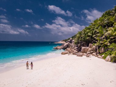 Seyşeller tropikal adaları, Praslins Adası Seyşeller çifti palmiye ağaçlarıyla tropik sahilde yürüyor.