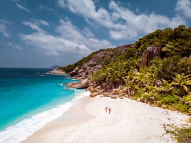 Seyşeller tropikal adaları, Praslins Adası Seyşeller çifti palmiye ağaçlarıyla tropik sahilde yürüyor.