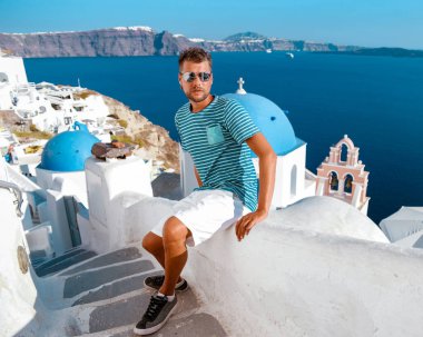 Yunanistan 'da tatil yapan Yunanistan' da Oia Santorini, Yunanistan 'da tatil yapan Yunanistan' da Yunan kiliseleri olan Oia beyazlatılmış köye lüks bir gezi düzenleyen adam.