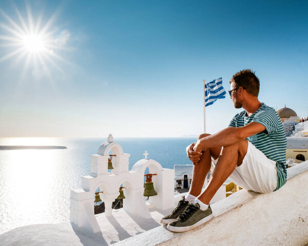 man on vacation Greece visisting Oia Santorini, guy on holiday in Greece on a luxury trip to Oia whitewashed village with Greek churches