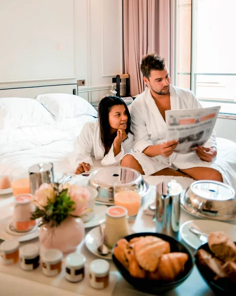 Morning wake up in bed in Paris with breakfast coffee and a newspaper, couple in bed men and woman honymoone valentine couple — Stockfoto