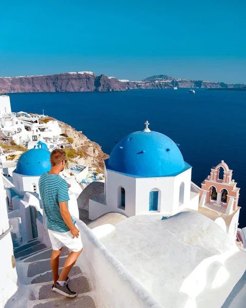 在希腊度假的男人欣赏Oia Santorini，在希腊度假的男人带着希腊教堂去了Oia粉刷过的村庄 — 图库照片