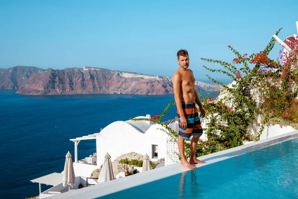 man on vacation Greece visisting Oia Santorini, guy on holiday in Greece on a luxury trip to Oia whitewashed village with Greek churches