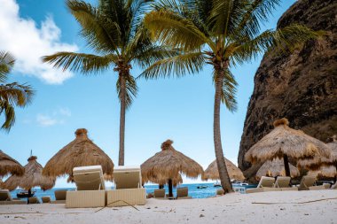 St. Lucia Adası plajında palmiye ağaçları ve lüks plaj sandalyeleriyle halka açık beyaz bir plaj olan Saint Lucia.