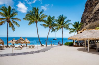 St. Lucia Adası plajında palmiye ağaçları ve lüks plaj sandalyeleriyle halka açık beyaz bir plaj olan Saint Lucia.