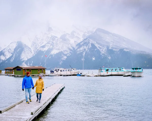 Lake Minnewanka Banff parque nacional Canadá, casal andando junto ao lago durante tempestade de neve em outubro nas Montanhas Rochosas canadenses Canadá — Fotografia de Stock