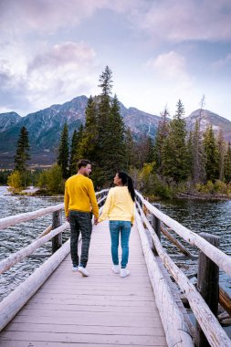 Çiftler göl kenarında gün batımını izliyor, Alberta Kanada 'da sonbahar boyunca Jasper Piramidi, günbatımında göl kenarına düşen renkler, Jasper Piramidi.