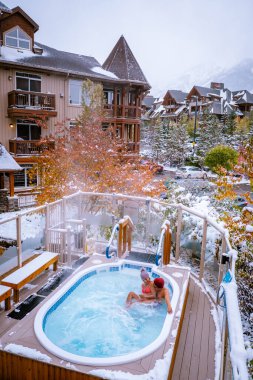 couple in hot tub during snow in the Canadian rockies in Canada, men and woman in hot tub